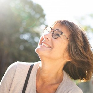 Smiling woman with glasses looking up toward the sky