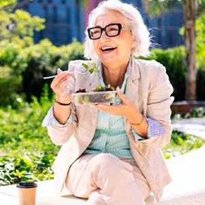 Older woman eating a salad on an outdoor bench
