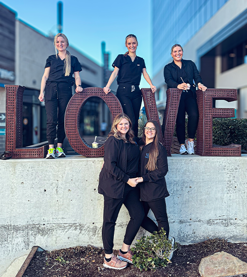 Dental team members standing around large letters spelling LOVE