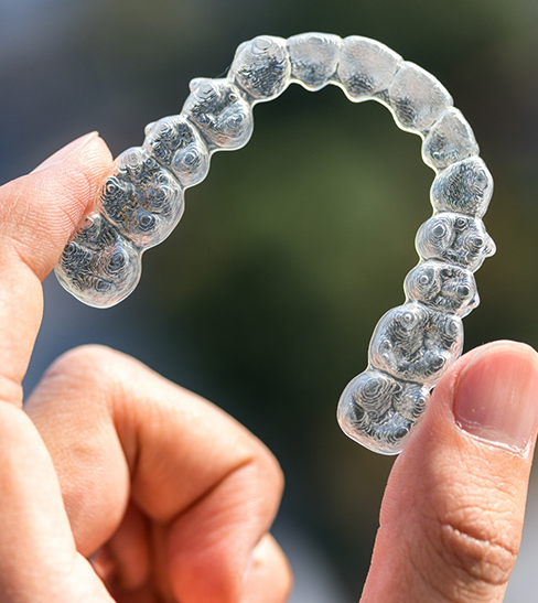 Close-up of hand holding clear aligner