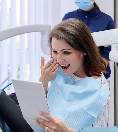 Female patient smiling and checking handheld mirror