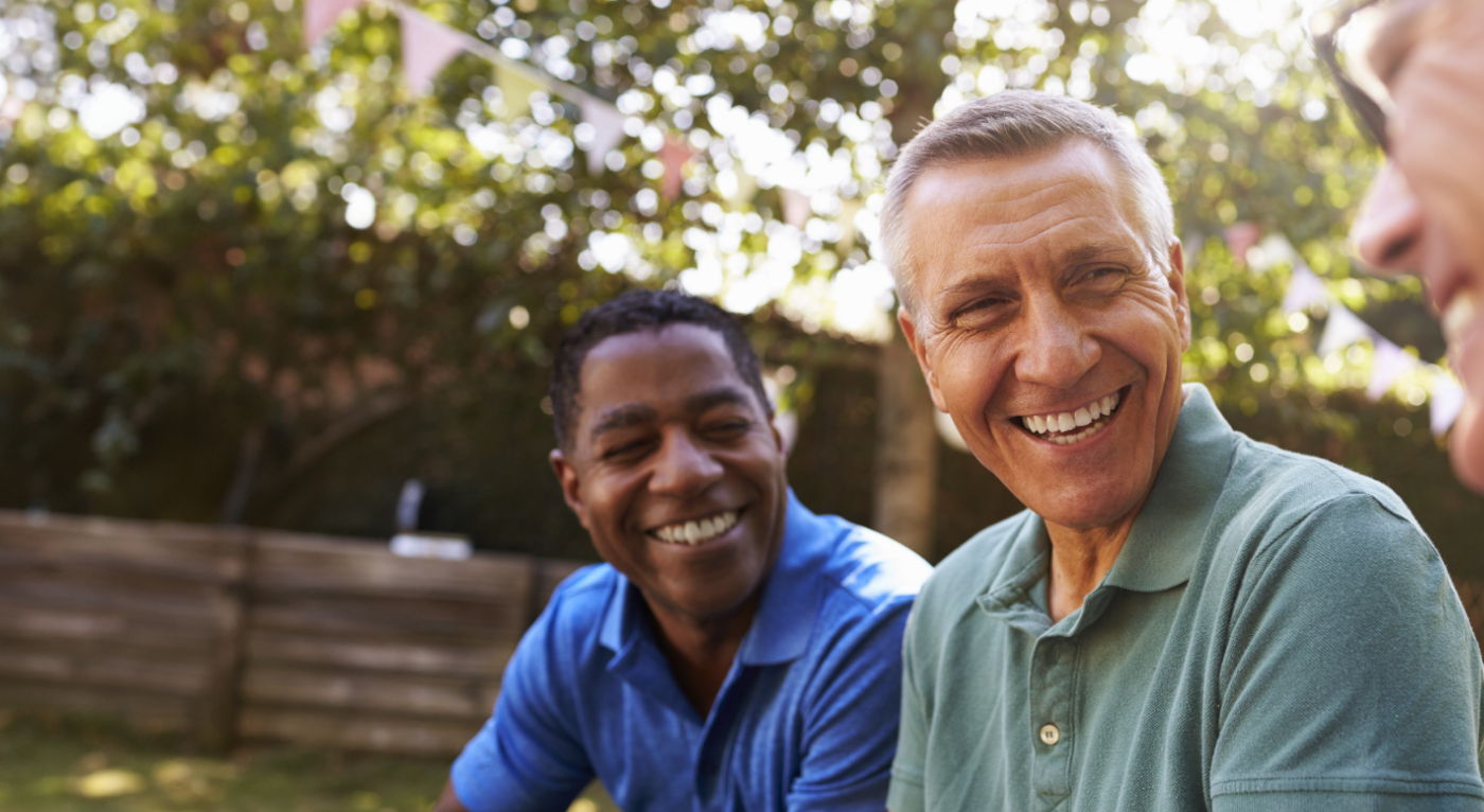 Three men in collared shirts laughing outside