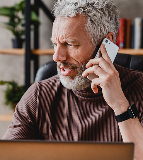 Concerned man with brown shirt talking on phone