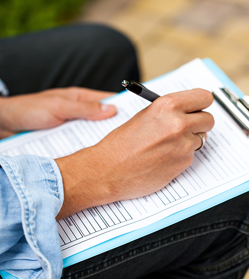 Close-up of person filling out form on clipboard