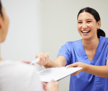 Female dentist handing clipboard and pen to patient