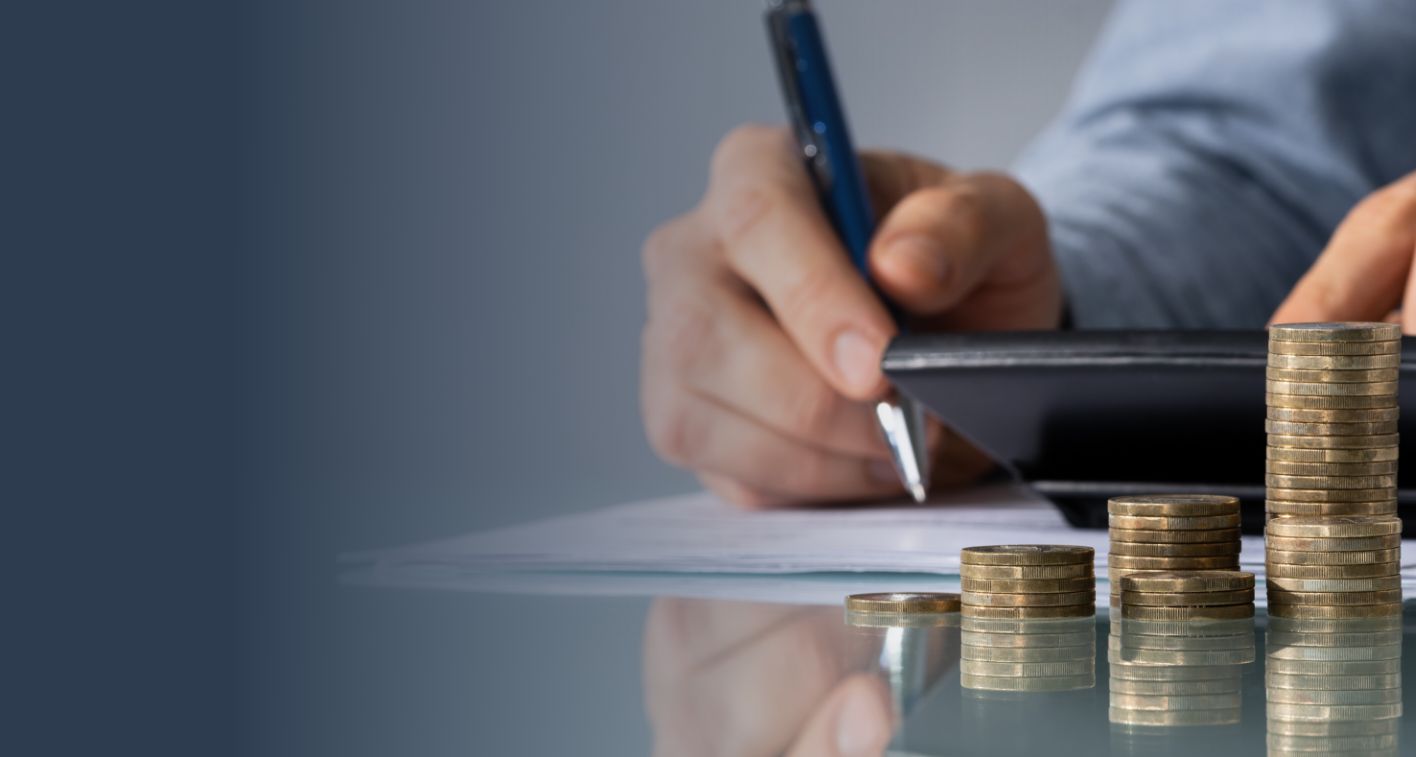 Close-up of coins in foreground and person looking at tablet in background