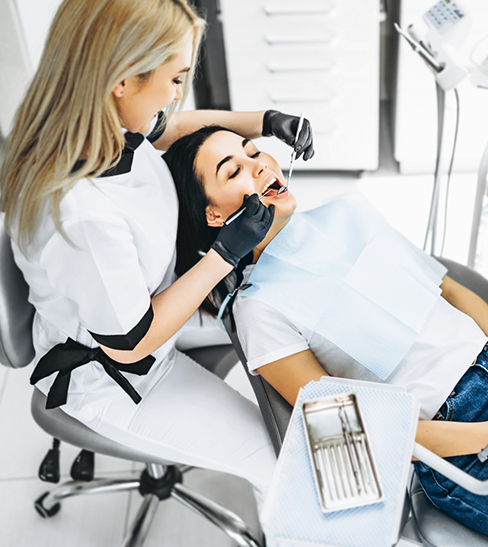 Female patient receiving checkup and cleaning from female dentist