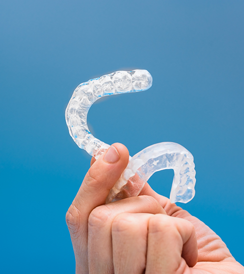 Close-up of hand holding two nightguards for bruxism