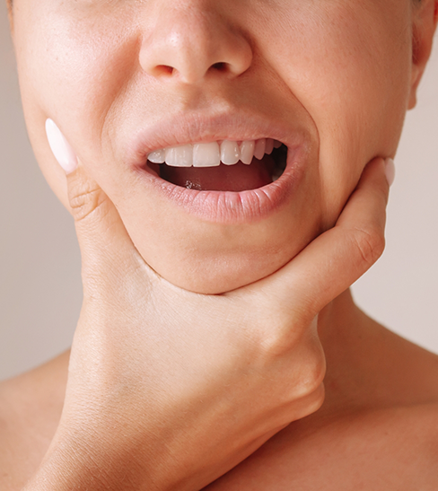 Close-up of woman with TMJ disorder rubbing jaw