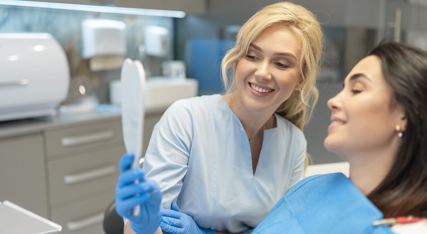 Female dentist showing female patient a dental restoration